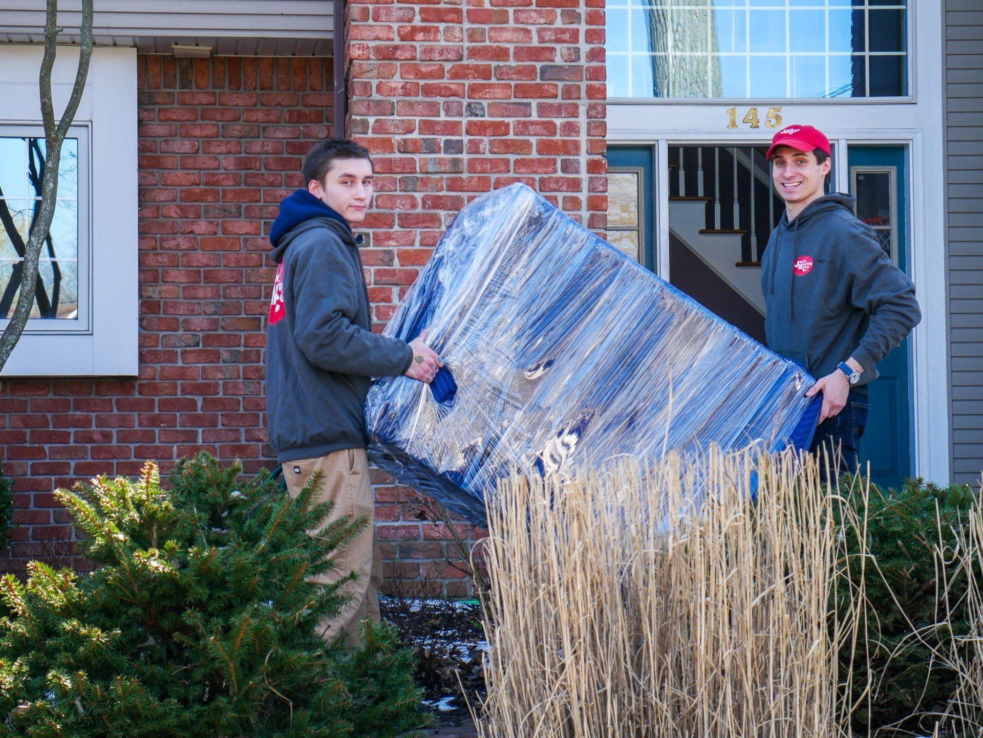 Movers carrying wrapped furniture from a home